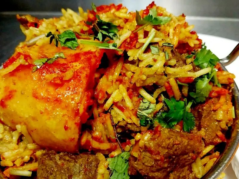 Lamb breyani with basmathi rice, potato and coriander in a steel bowl