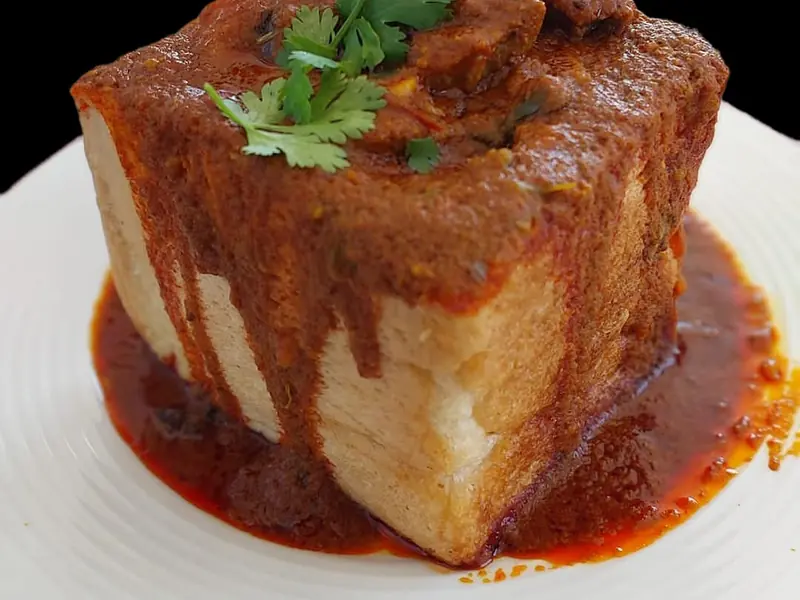 Quarter lamb bunny chow, curry poured over the loaf and topped with coriander